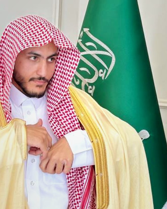 المحامي سالم خلف الشمري بالبشت، وبجانبه علم المملكة العربية السعودية
